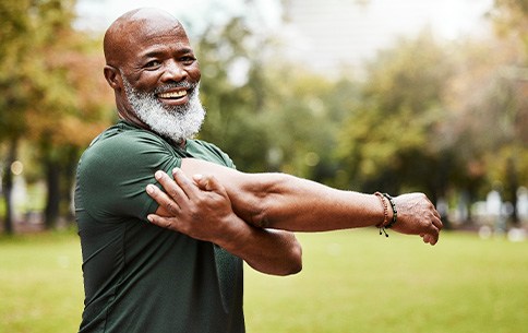 Senior man stretching outside and smiling