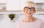 Senior woman with glasses smiling in kitchen