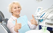 Senior woman giving a double thumbs up in dental chair