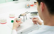 Lab tech carving a set of dentures on a cast