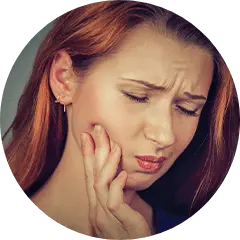 Woman with red hair holding her cheek in pain