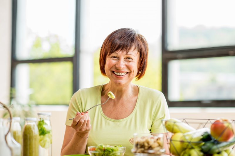 Patient smiling while eating with dentures