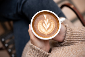 Top-down view of woman in sweater holding a cute cup of coffee